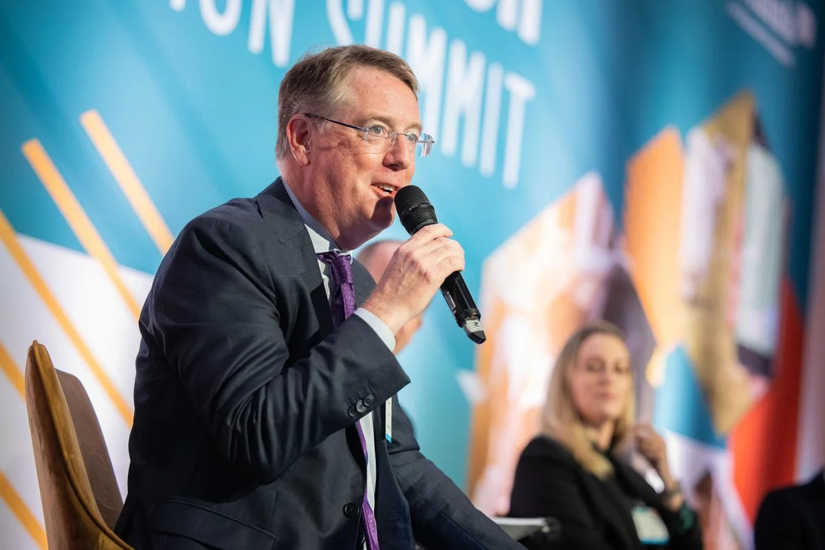 Aidan Connolly holding a microphone during a panel discussion at a professional summit, highlighting expertise and engagement in global agriculture and food systems.