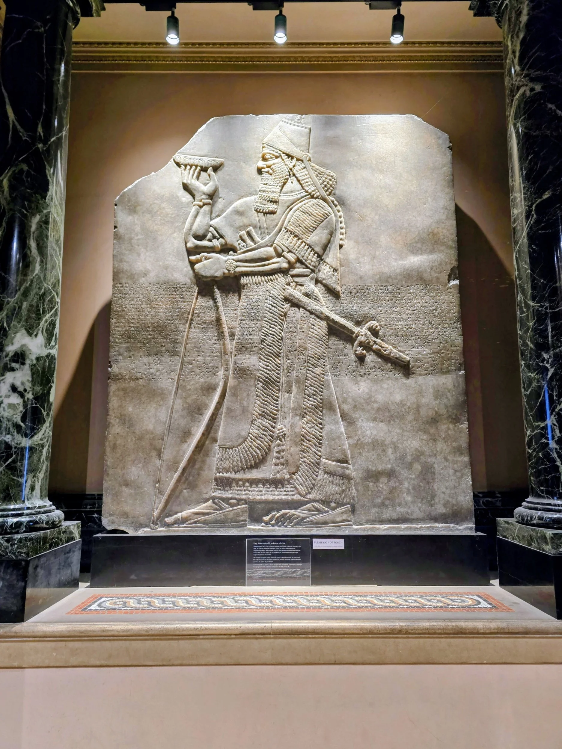 King Ashurnasirpal II relief (883–859 BC) at the Fitzwilliam Museum shows a royal ritual with cuneiform inscriptions.