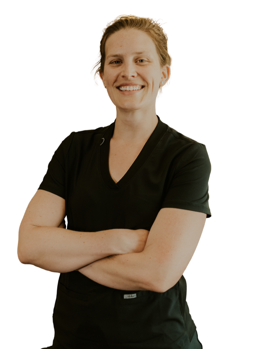 A female dentist with short light brown hair smiling with crossed arms, wearing a black scrubs.