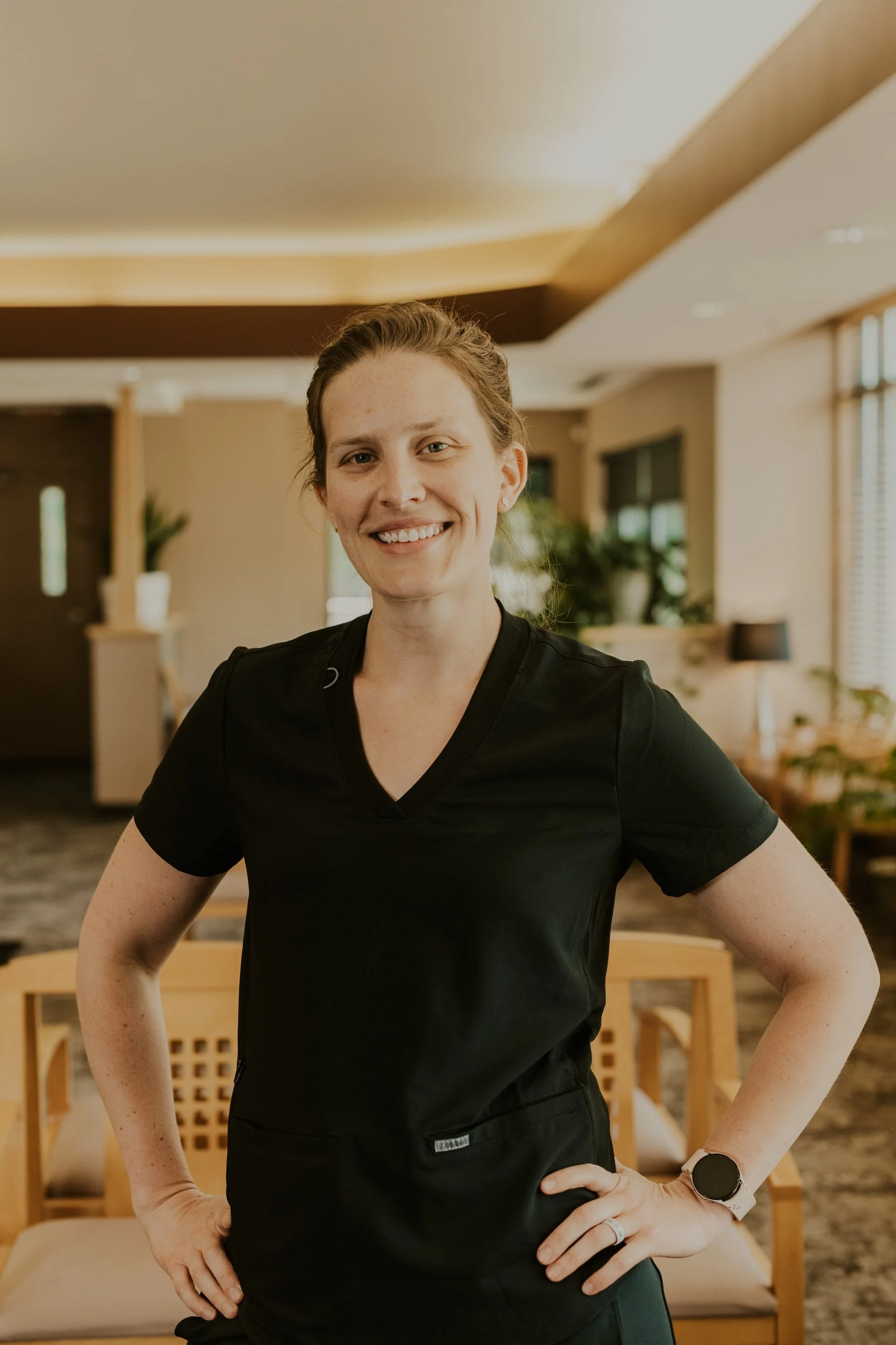 Dr. Amanda De Los Rios smiling while wearing black scrubs and standing in the Lakeville Family Dental office.