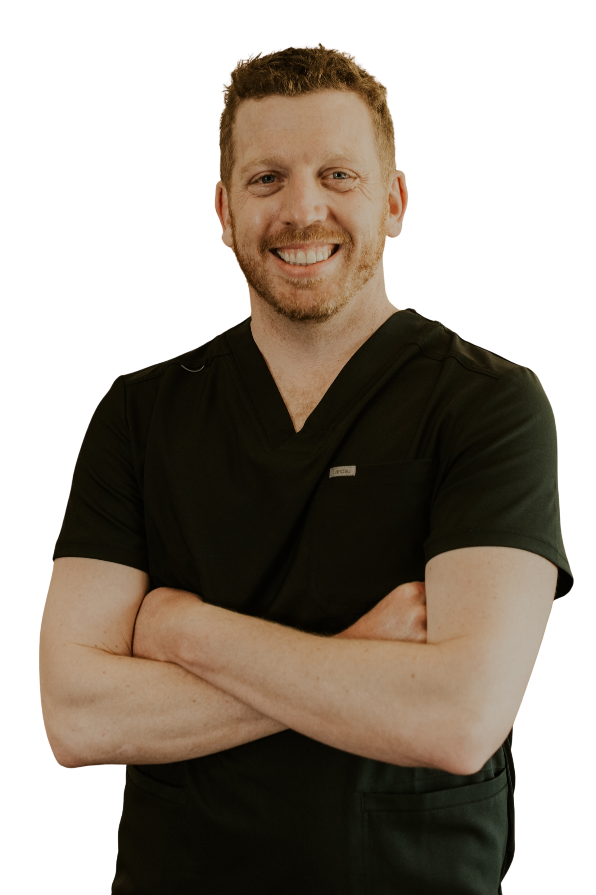 A smiling man with closed arms wearing black dental scrubs.