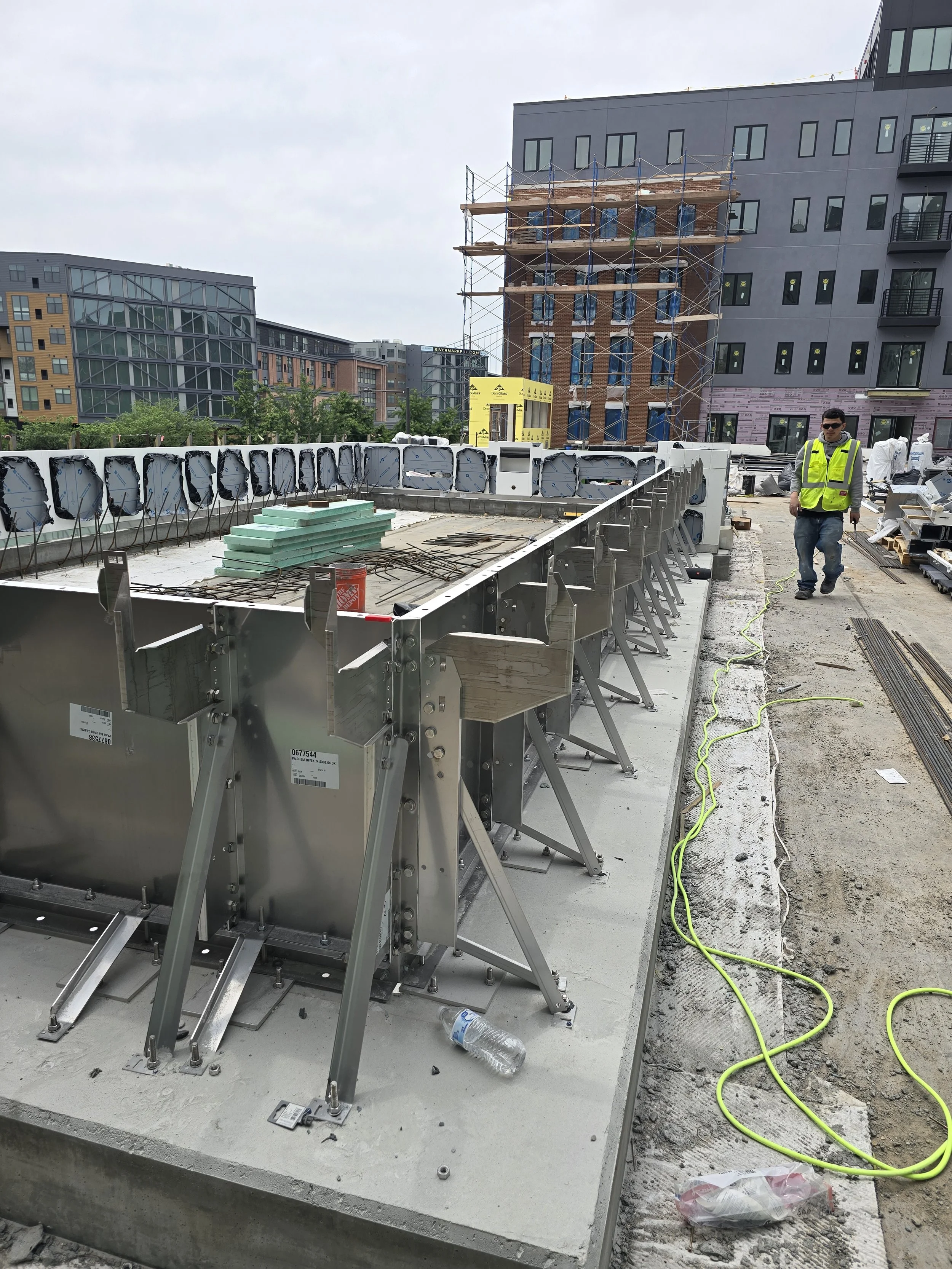 Construction site with workers, scaffolding, and unfinished building in an urban area.