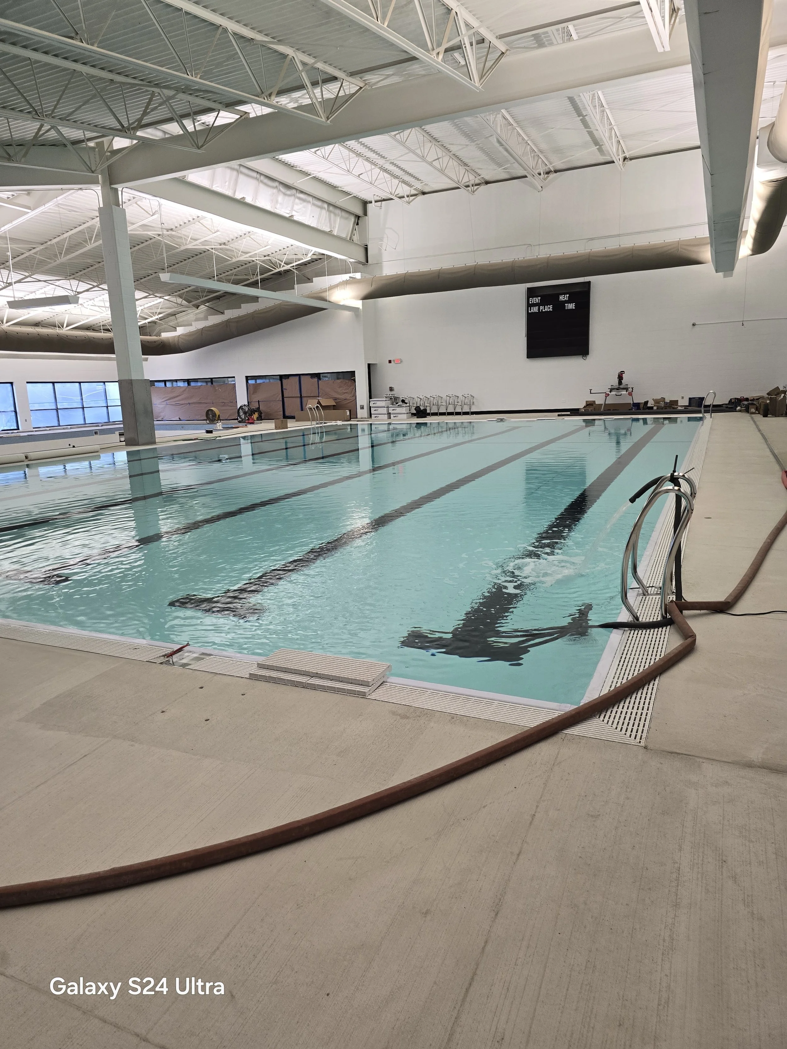 Indoor swimming pool with lanes and a large display screen on the wall - Caribbean Paradise & Aquatics LLC