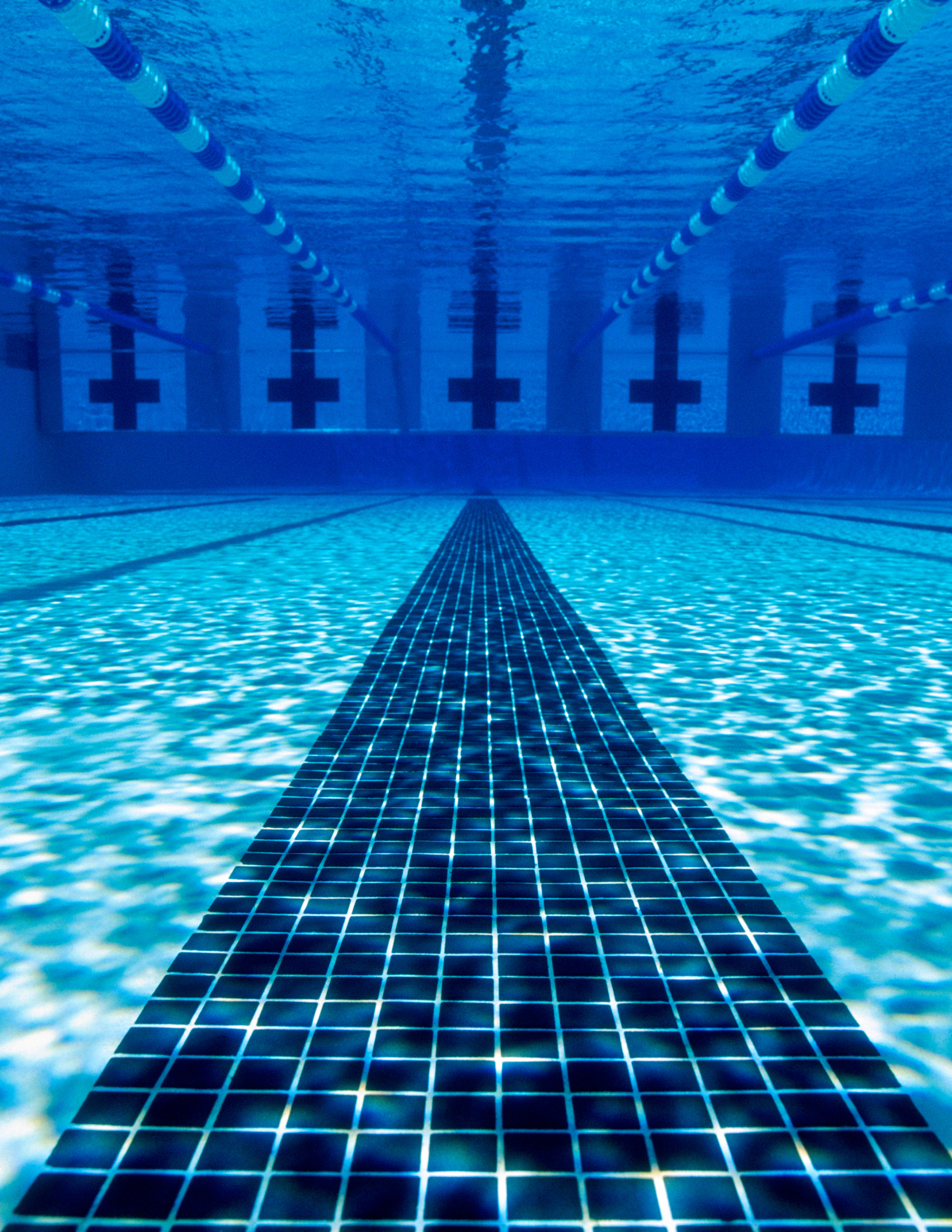 Underwater view of a swimming pool with lane markers and a clear tiled lane divider.