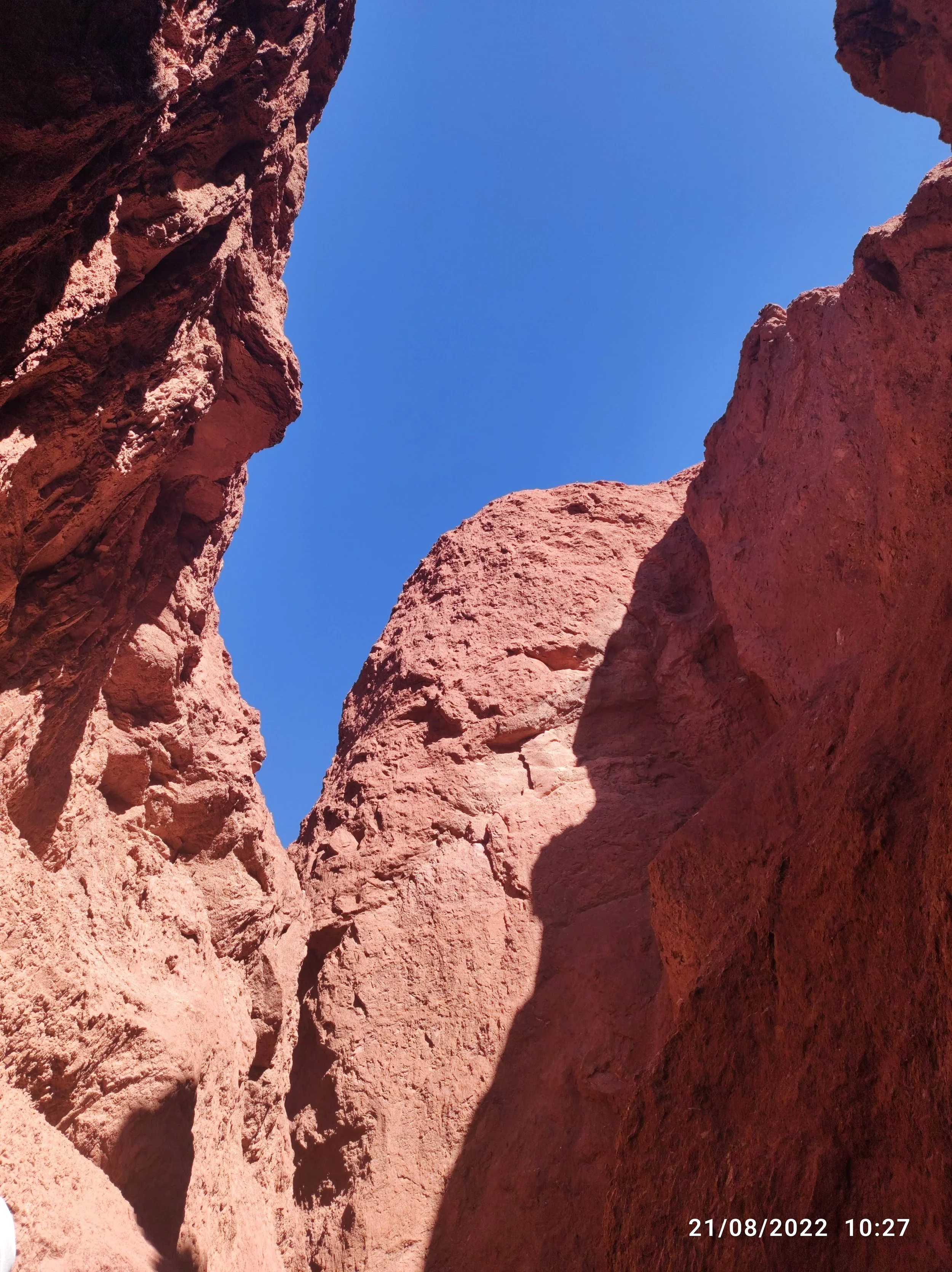 Red rocky canyon walls with a clear blue sky visible above.