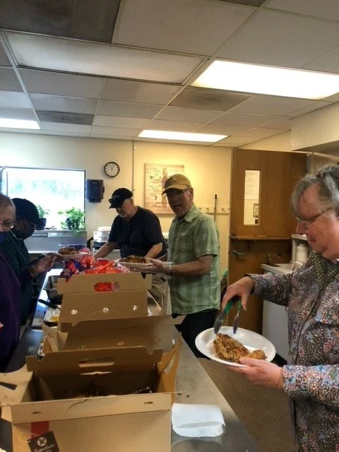 People serving and receiving food in a community kitchen or church setting.