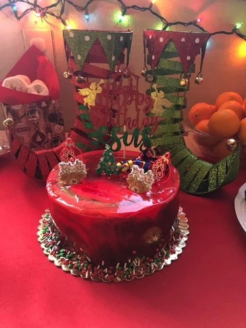 A Halloween-themed birthday party table with a red cake, Christmas decorations, and orange fruit in a bowl.