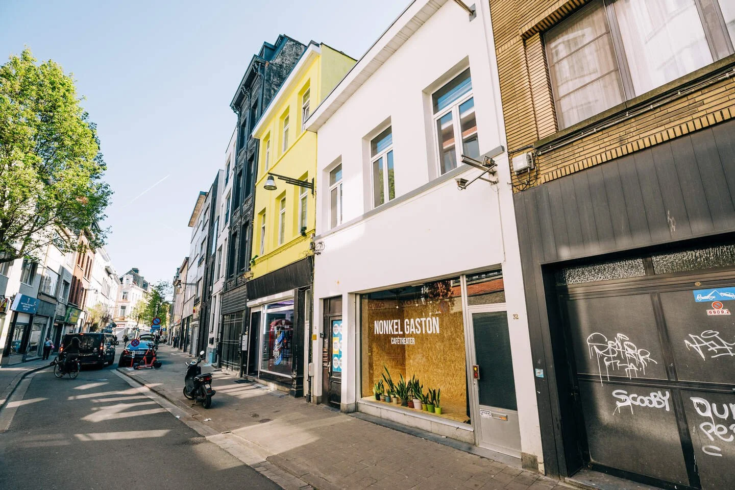 Uitstraling van een winkelstraat, de Diepestraat, met diverse winkels en gebouwen in verschillende kleuren. Een etalage in OSB met sanseveria's. Nonkel Gaston.