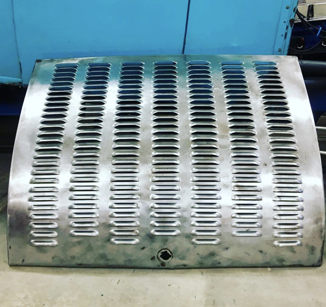 Metal vent cover with multiple elongated vents, placed on a flat surface with a blue background.
