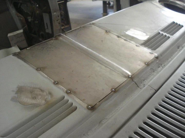 Close-up of a metal panel on a piece of machinery, with visible screws and vents.