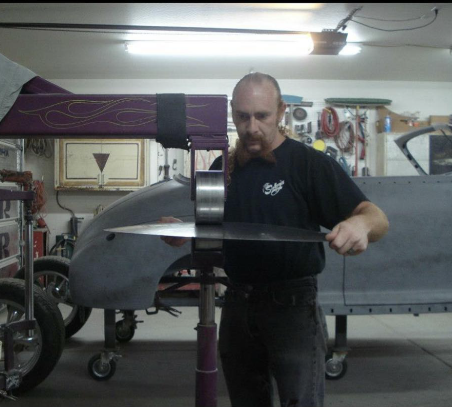 A man working on an aircraft inside a garage or workshop, with various tools and equipment in the background.