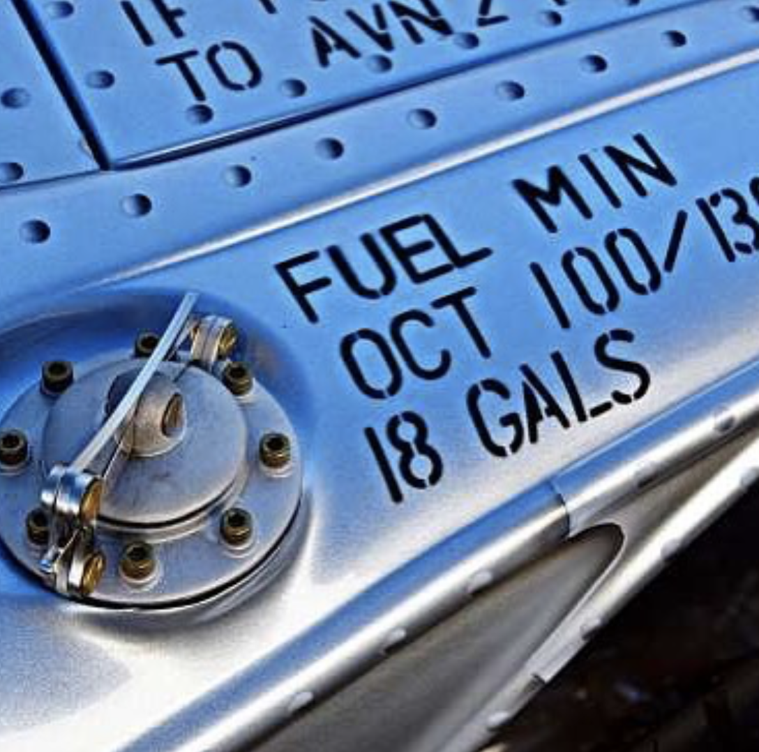 Close-up of a fuel pump meter displaying 18 gallons, with text indicating fuel capacity of 18 gallons, minimum octane oct 100, and date of October 13.