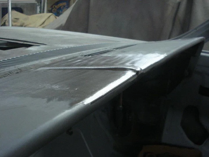 Close-up of a metal aircraft wing or fuselage in a workshop.