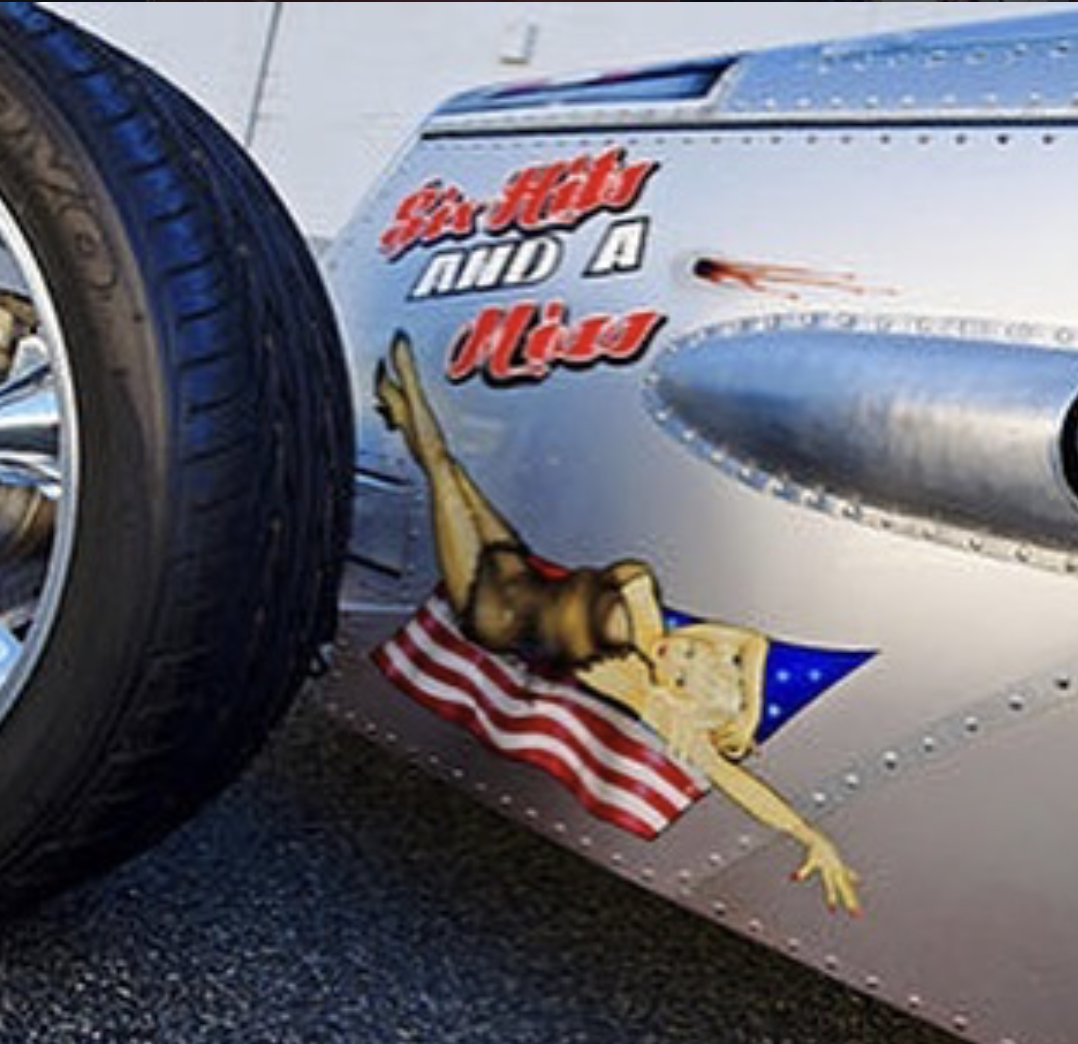 A race car with a cartoon illustration of a frog wearing a space helmet, pointing upward, with a small American flag. Text on the car reads, "Go H2O and A Hula."