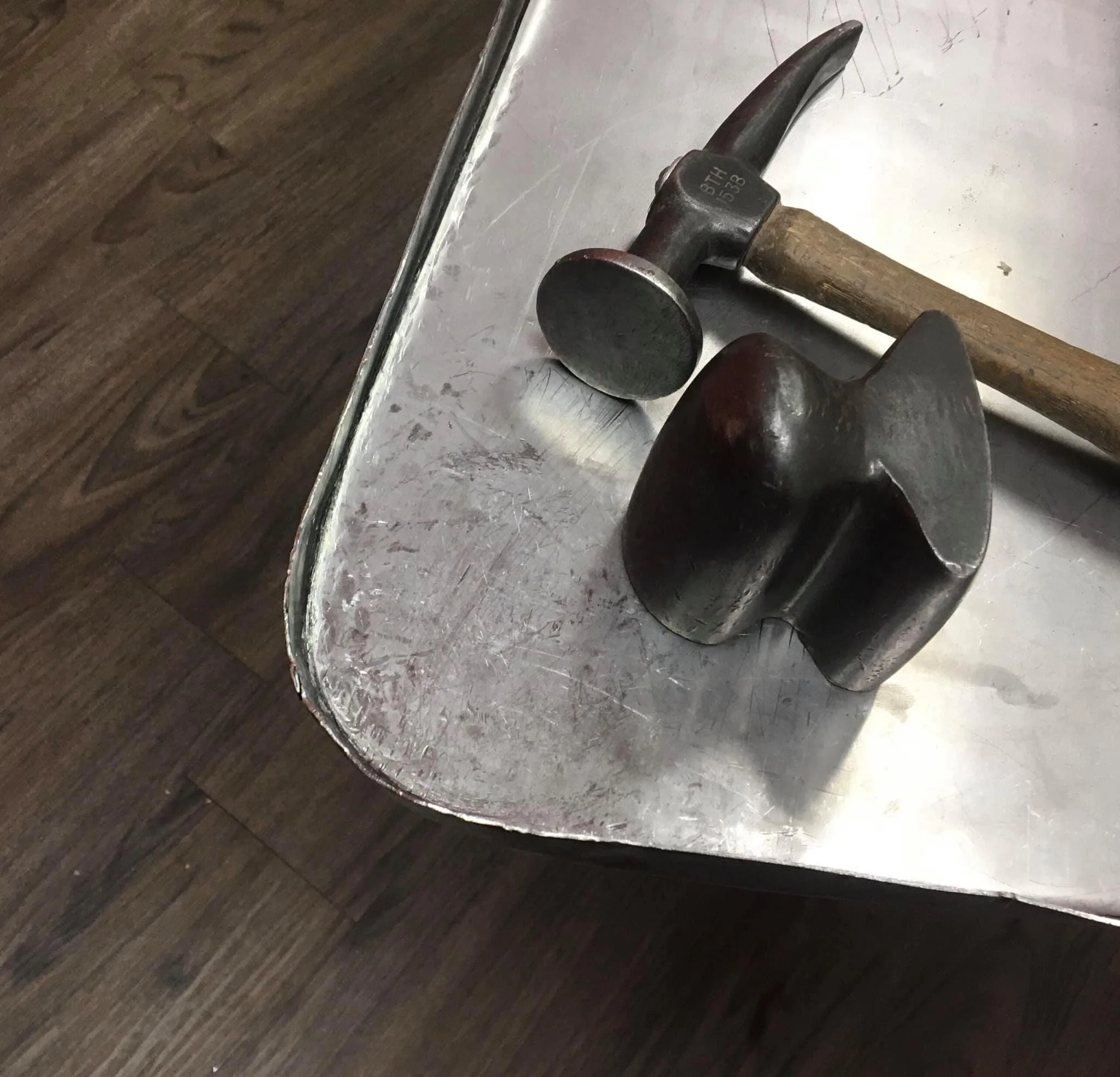 A metal table with a hammer and a black metal object on it.