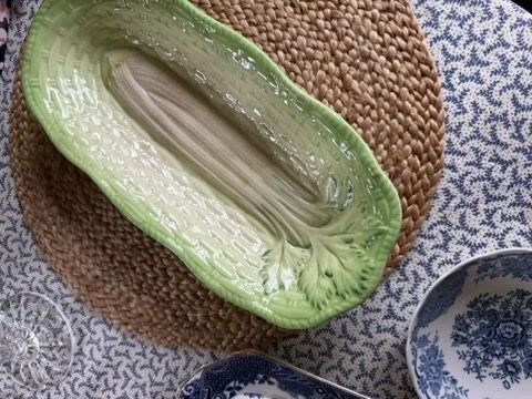 Empty green glass dish on a textured placemat with a blue and white patterned bowl nearby.