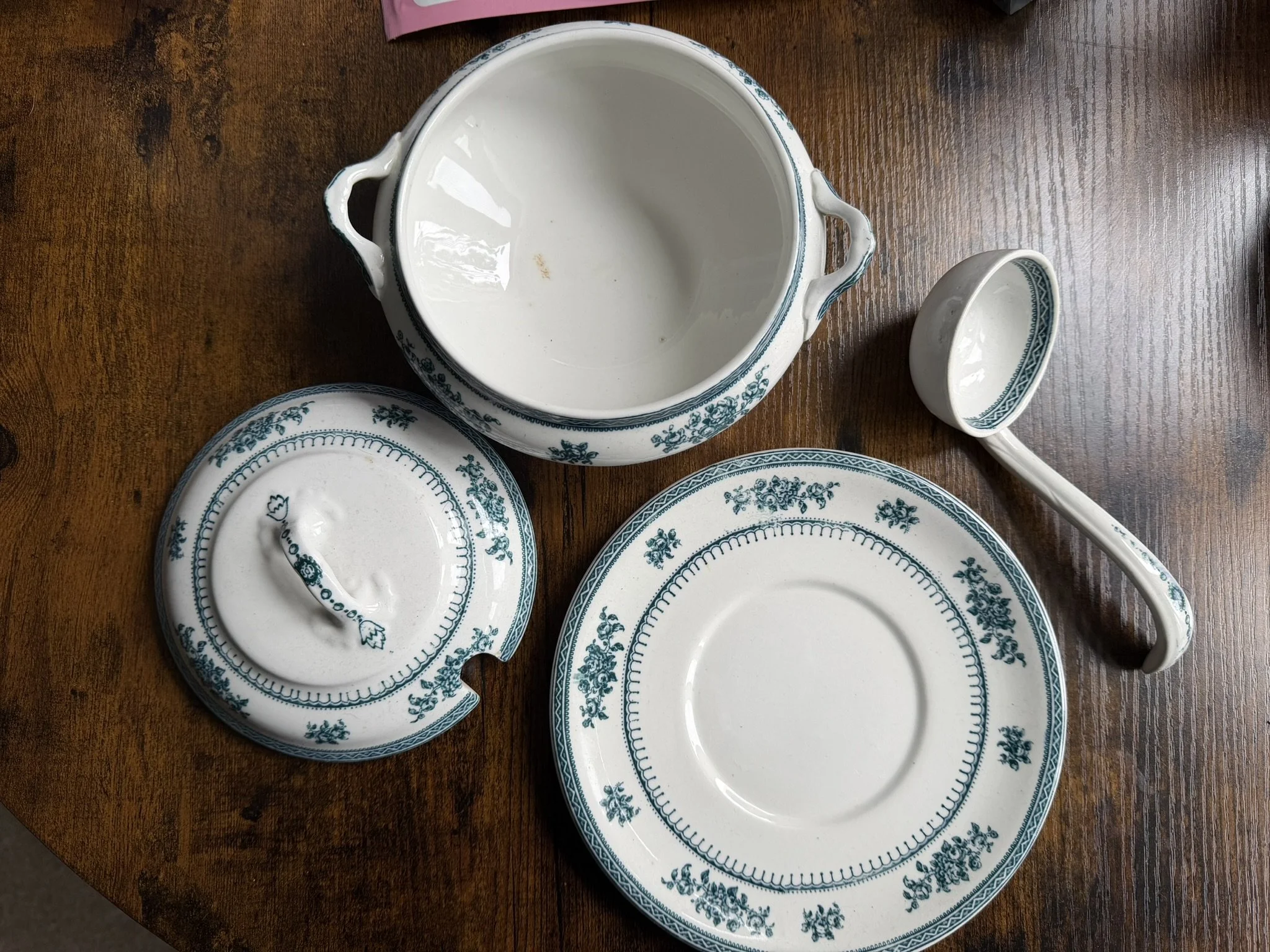 Set of vintage blue and white patterned porcelain dishes, including a large bowl, a smaller bowl, a plate, a spoon, and a lid, all placed on a wooden surface.