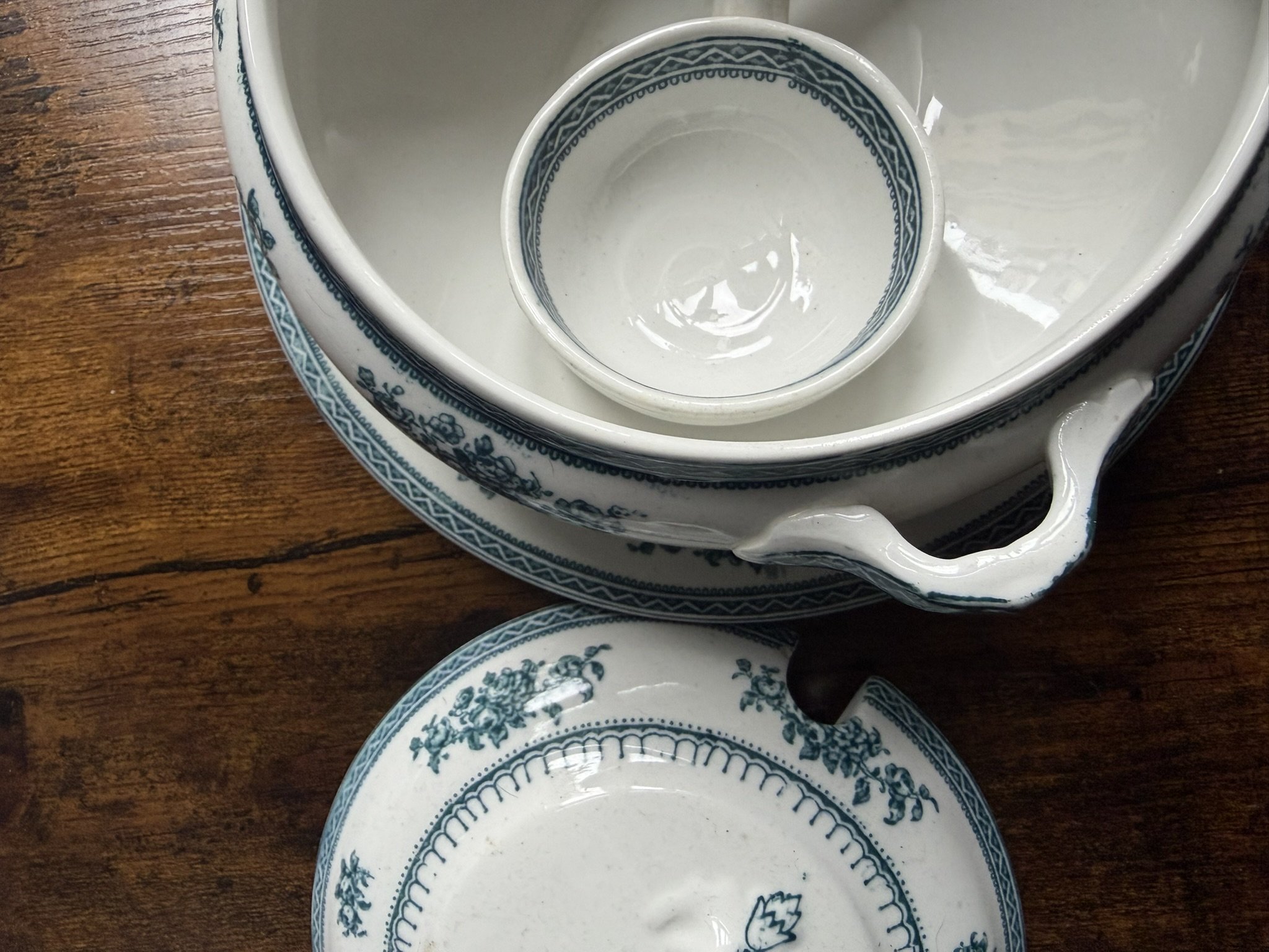 Blue and white patterned ceramic dishes and a small cup on a wooden surface.