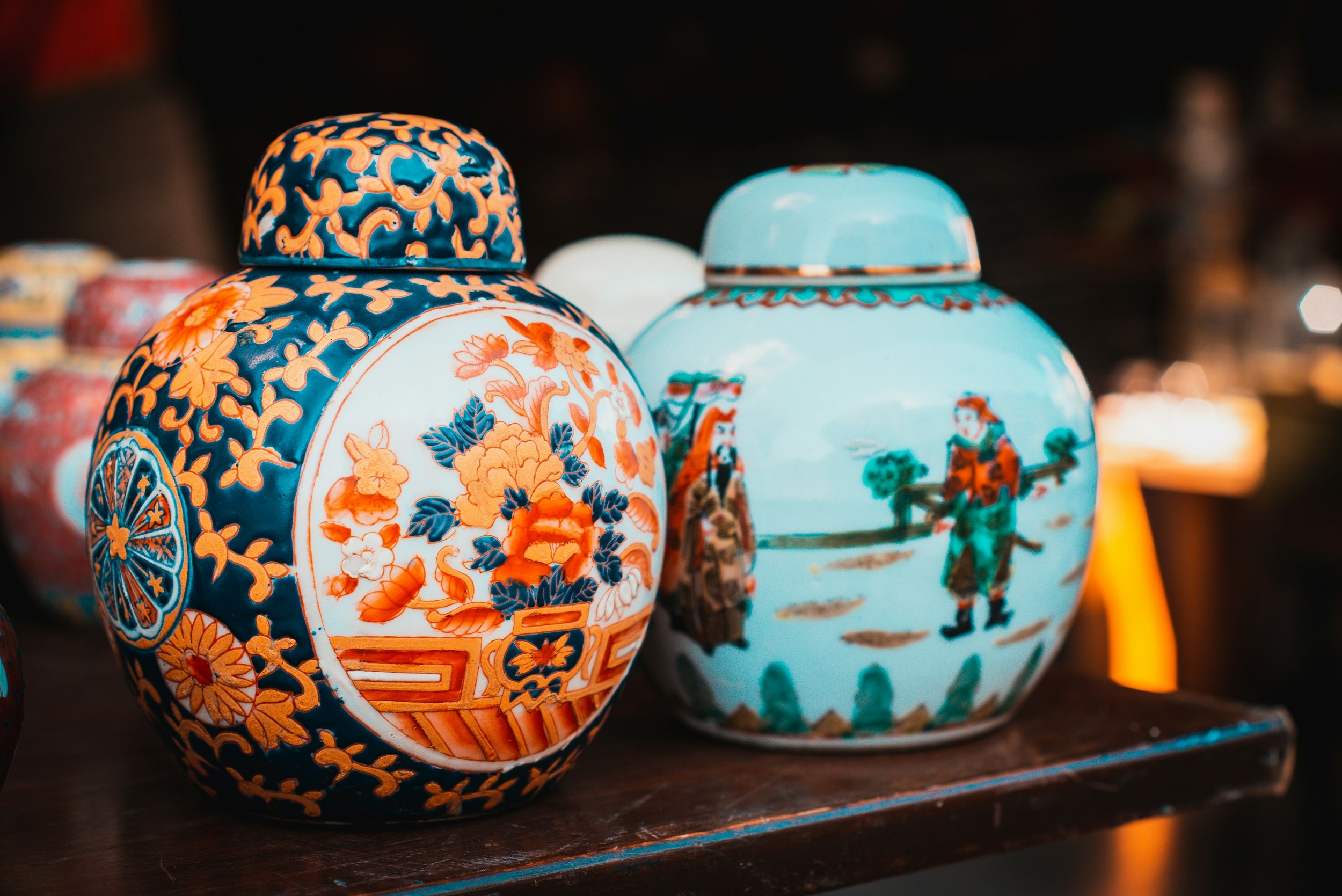 Colorful, ornate ceramic vases with intricate Asian-inspired designs displayed on a dark surface at night.