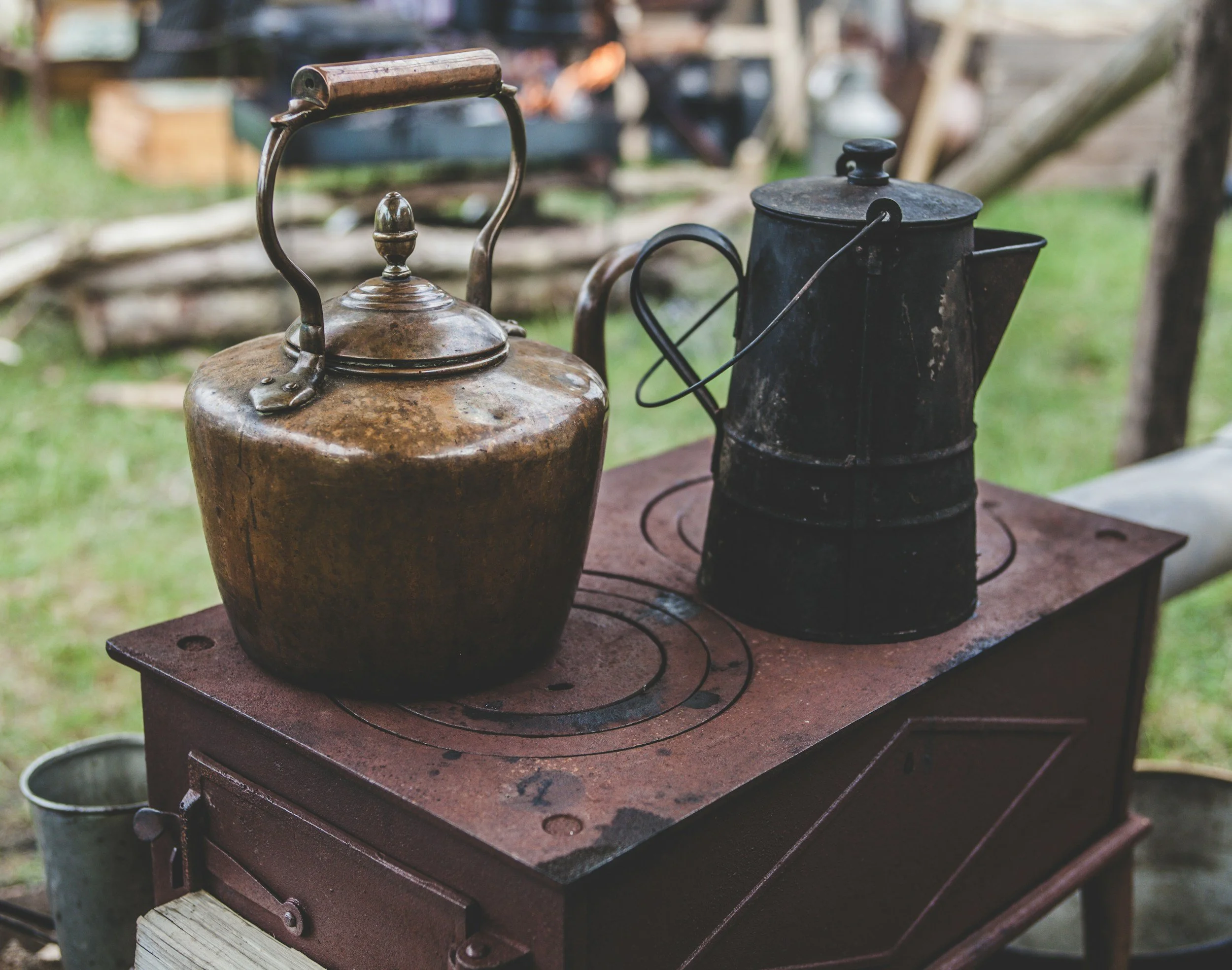 Old rusty teapot and black kettle on a stovetop outdoors