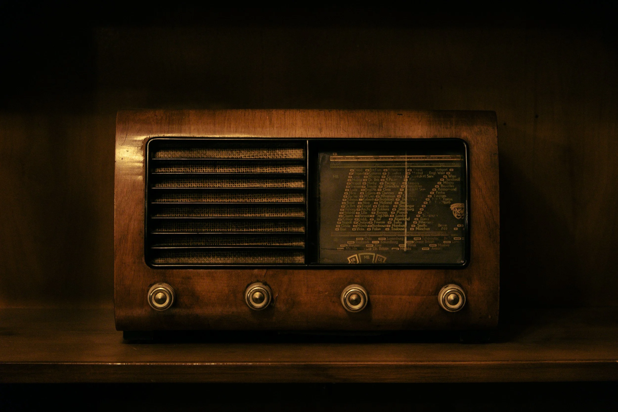 A vintage wooden tabletop radio with knobs and a large tuning dial.