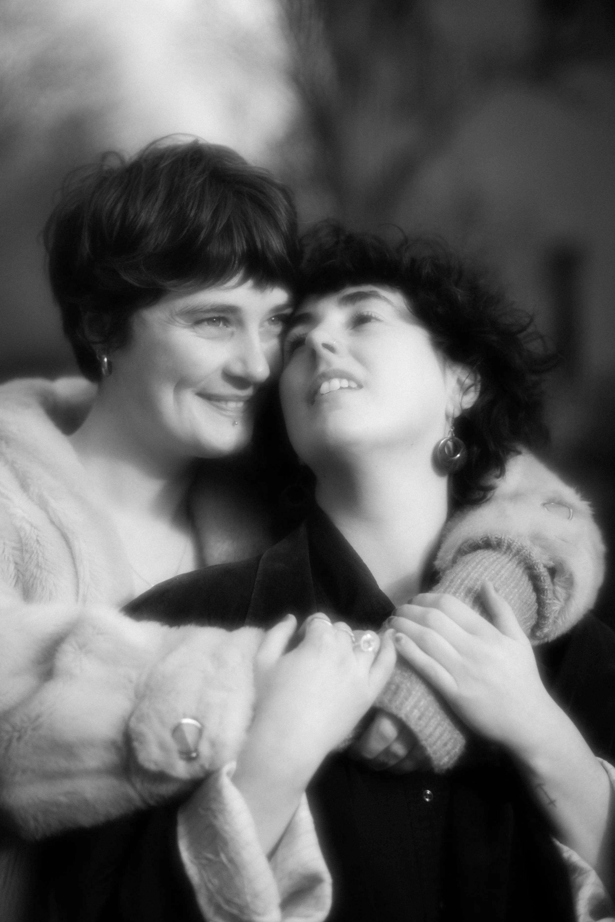 Two women embracing each other, smiling and looking at each other, in a black and white photo.