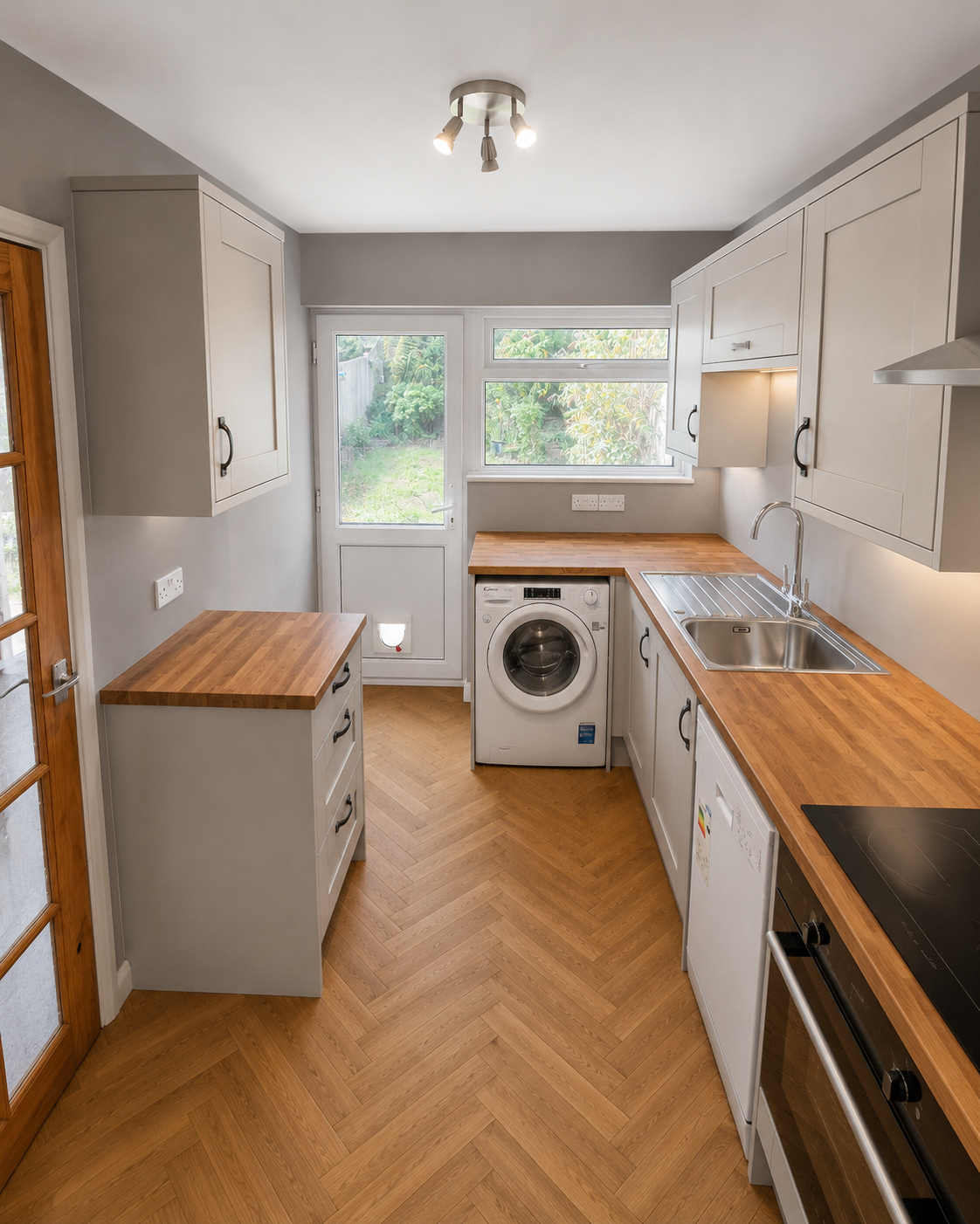 Completed shaker fitted kitchen in Camberley with wood-effect worktops, LVT herringbone flooring, integrated appliances, washing machine space, sink and neatly finished details by Blacktail Kitchens.