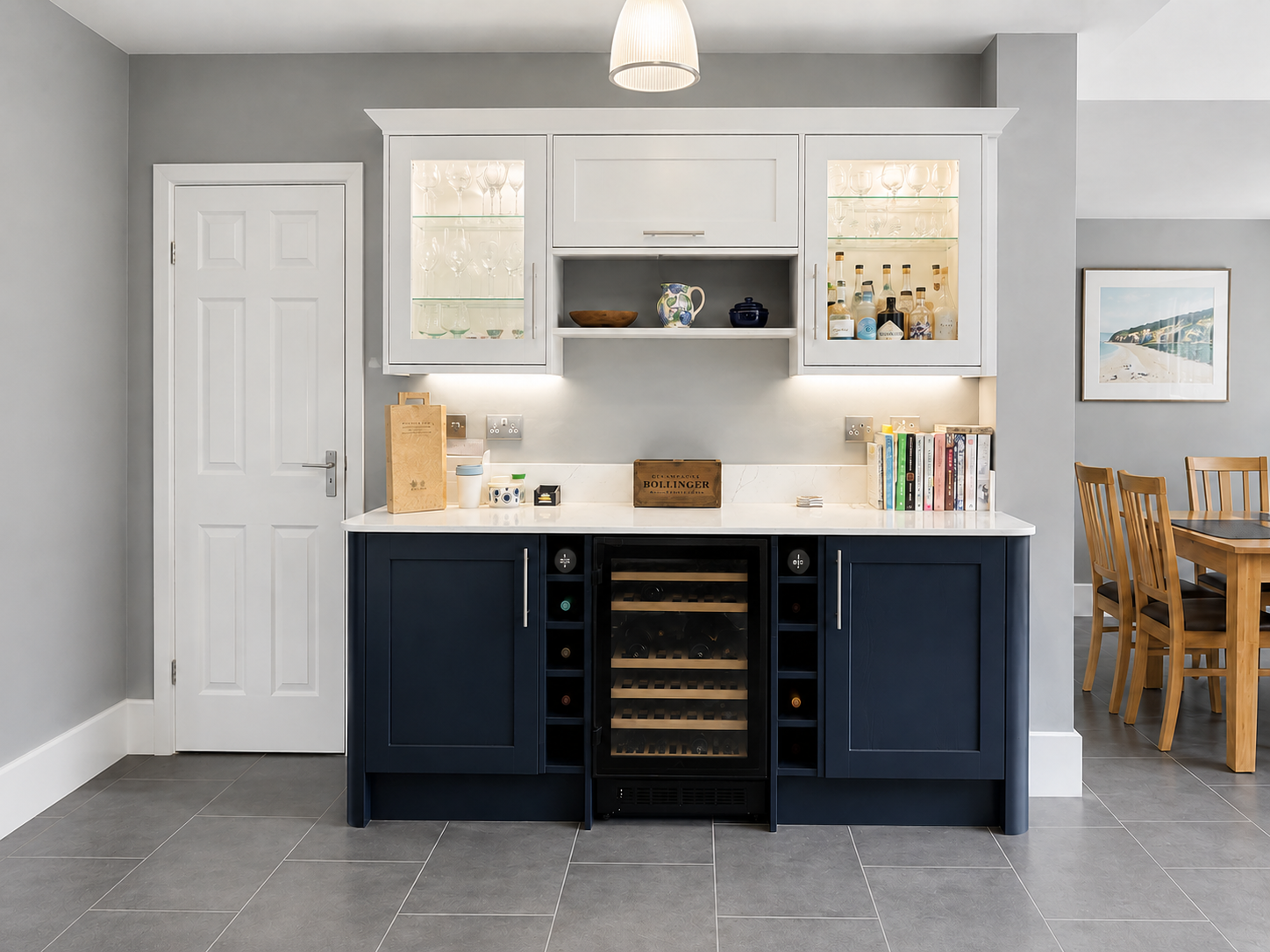 Navy kitchen island in Wokingham with white quartz worktops, skylights, grey walls, sink run, pendant lighting and slate grey LVT flooring by Blacktail Kitchens.