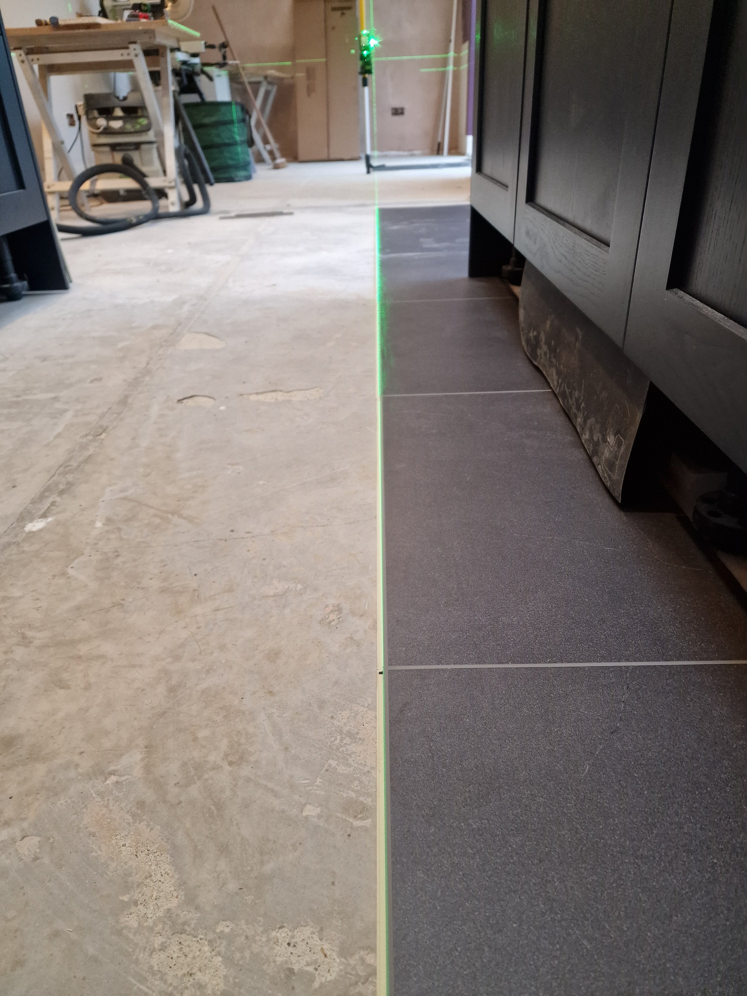Kitchen flooring installation in Wokingham using a laser line to set out the floor tiles accurately and ensure a straight, precise finish by Blacktail Kitchens.
