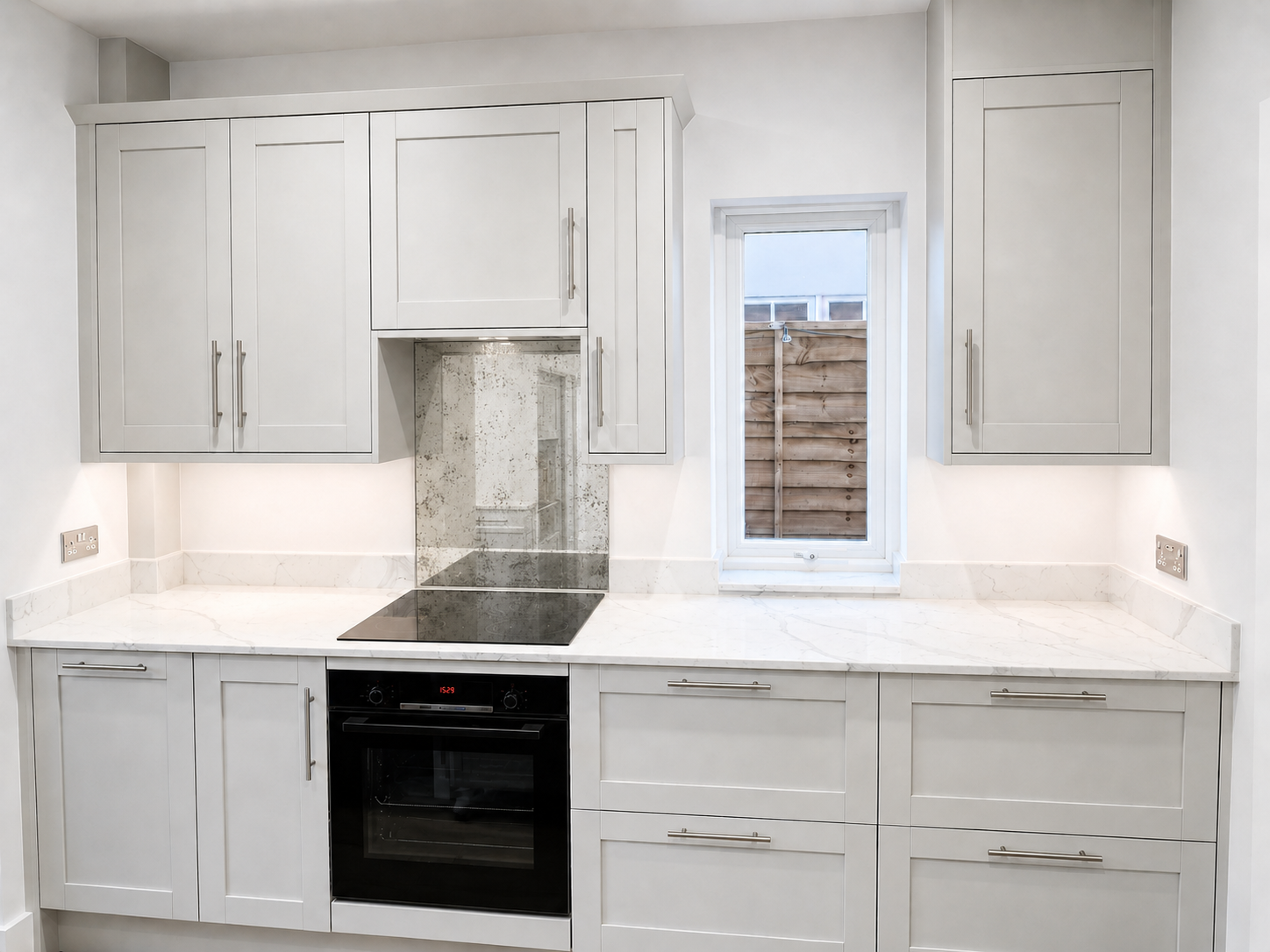Soft light grey shaker kitchen installation in Crowthorne with white quartz worktops, light grey veining, integrated appliances, Victorian mottled mirror splashback and carefully aligned cabinetry