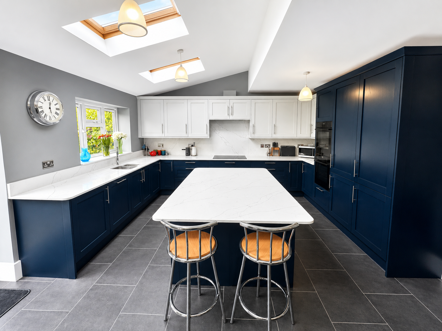 Modern kitchen with light grey & navy blue cabinets, white quartz countertops, and a central island.