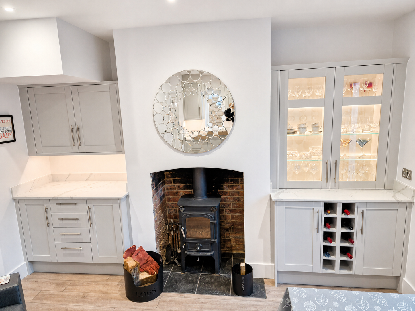 Matching fitted cabinetry in Crowthorne with light grey shaker units, illuminated glazed display cabinets, wine storage, fireplace storage and white quartz worktops.