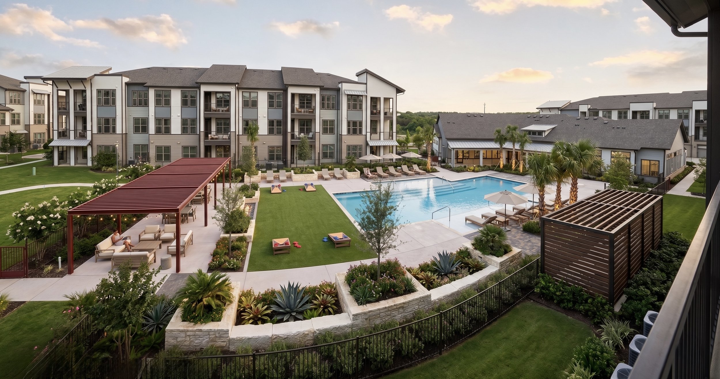 Apartment complex courtyard with swimming pool, lounge chairs, palm trees, and landscaped gardens at sunset.