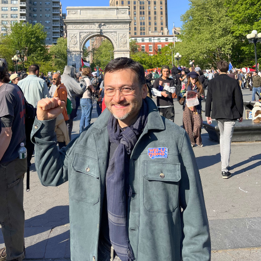 Wei-Li making a fist gesture at a demonstration, with the Washington Square Arch in the background.