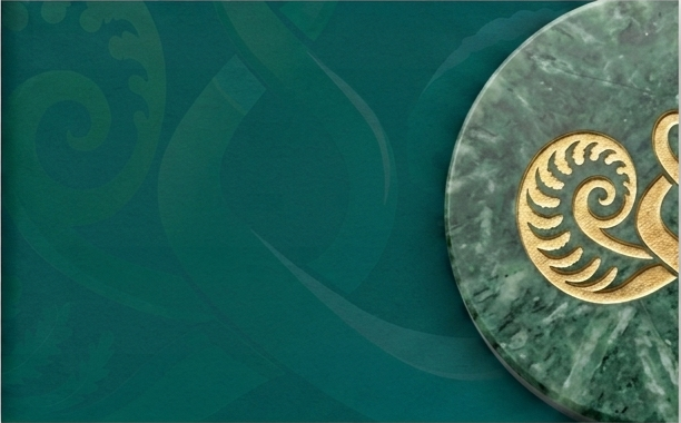 Close-up of a green marble coin with a golden swirl design on a teal background with faint decorative patterns.