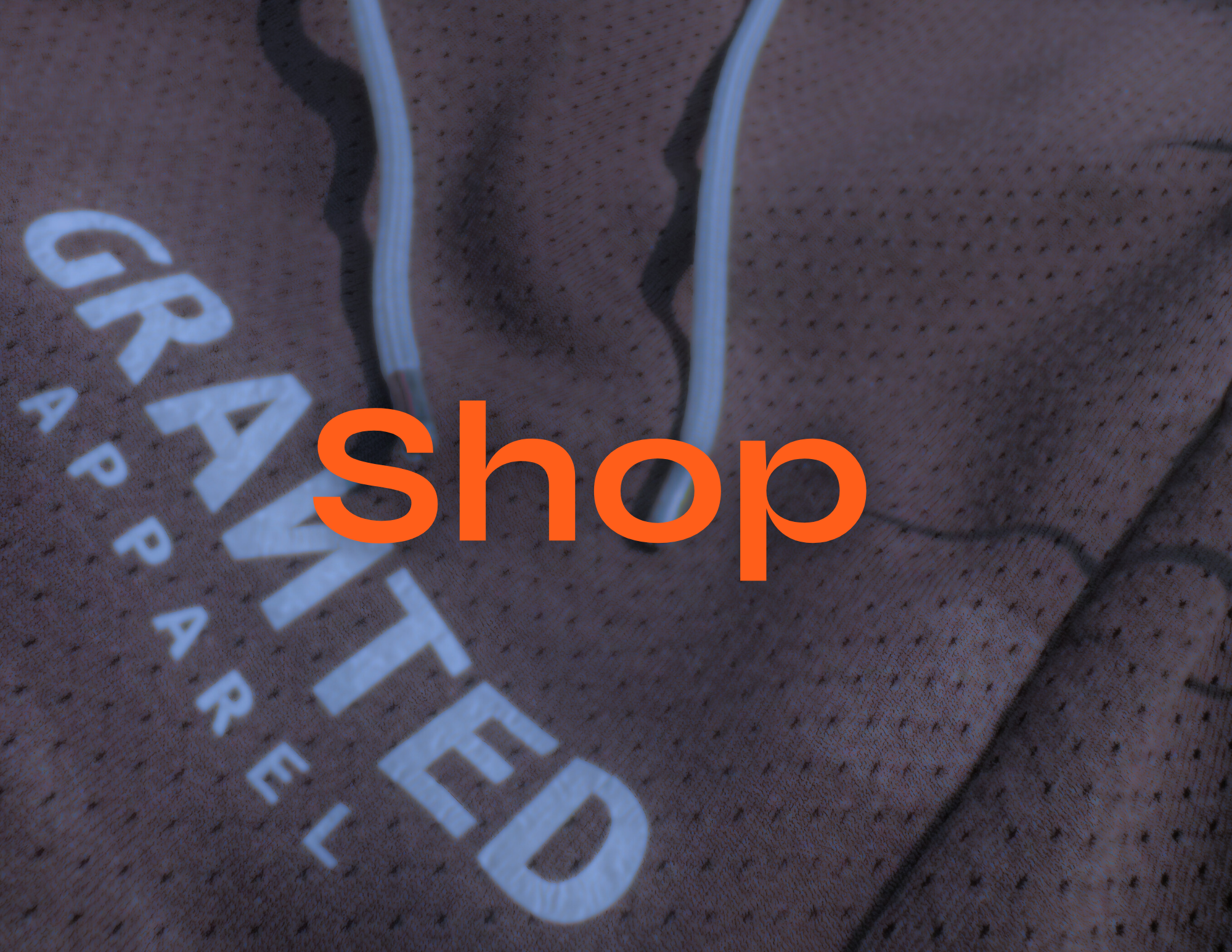 Close-up of a brown athletic shirt with the word 'GRIT' and the brand 'CATERPILLAR' printed on it, with a large orange 'Shop' overlay.