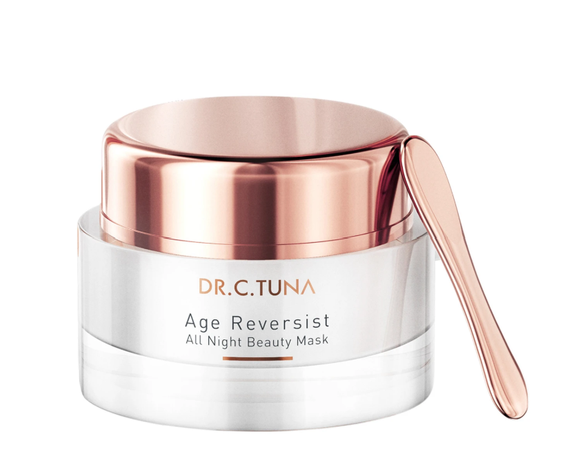 A skincare product container labeled Dr. C. Tuna Age Reversist All Night Beauty Mask with a rose gold spatula resting on the container.