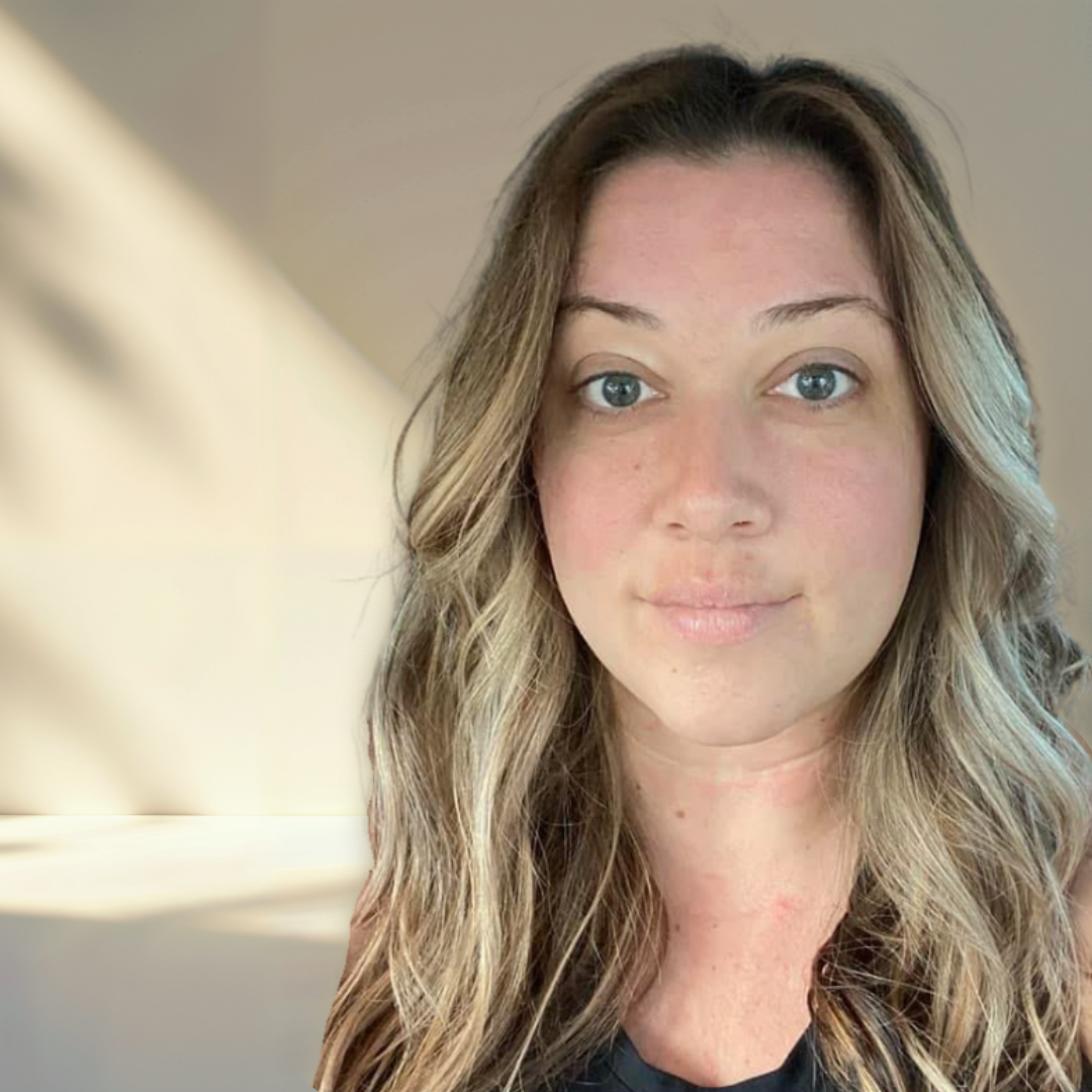 A woman with long, wavy blonde hair and blue eyes looking at the camera with a neutral expression.