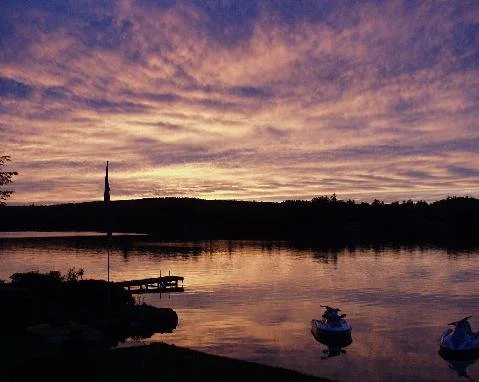 Sunset with dock and clouds reflected in the water.