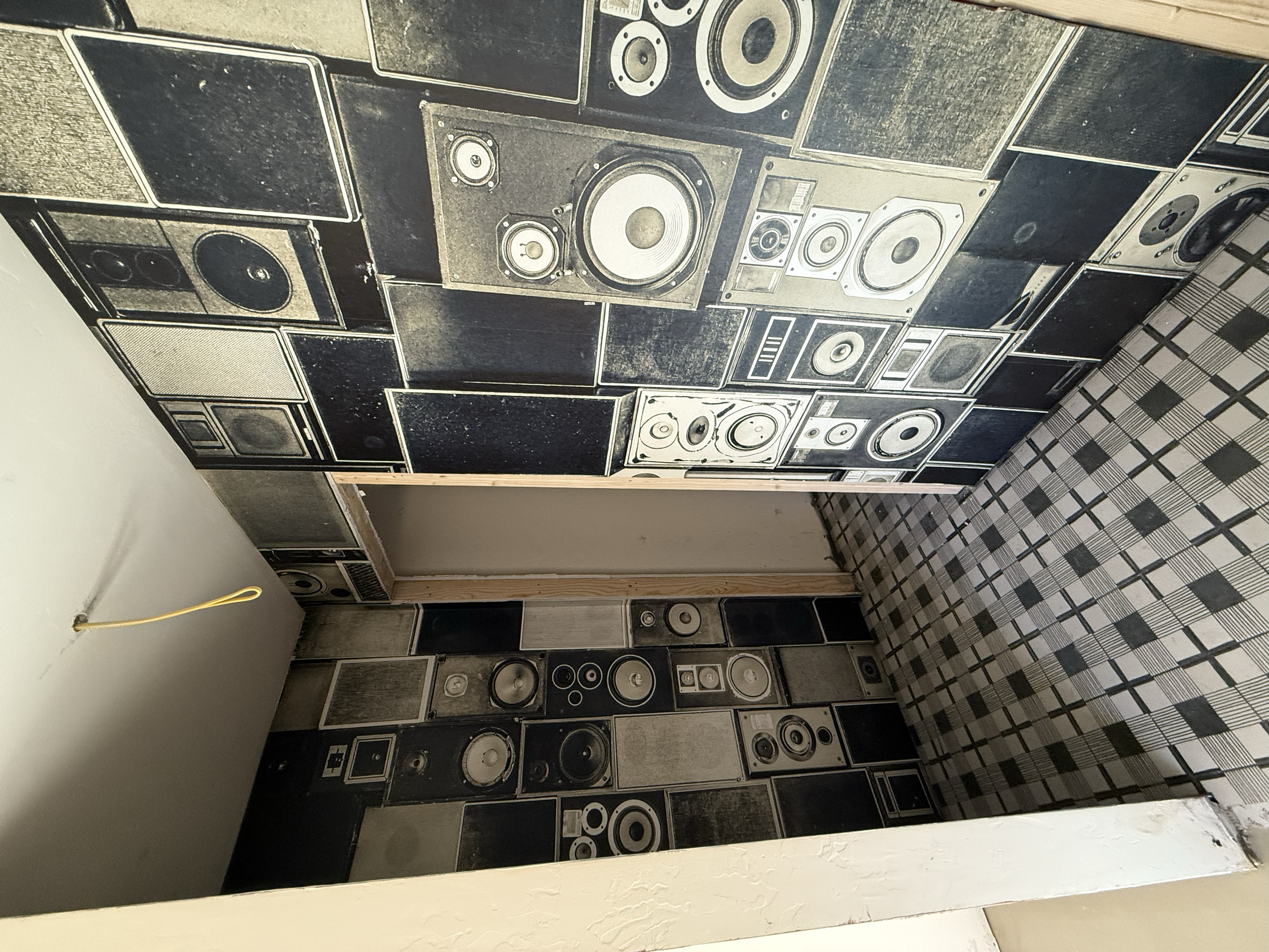 Room with walls covered in black and white speaker images, and a checkered floor