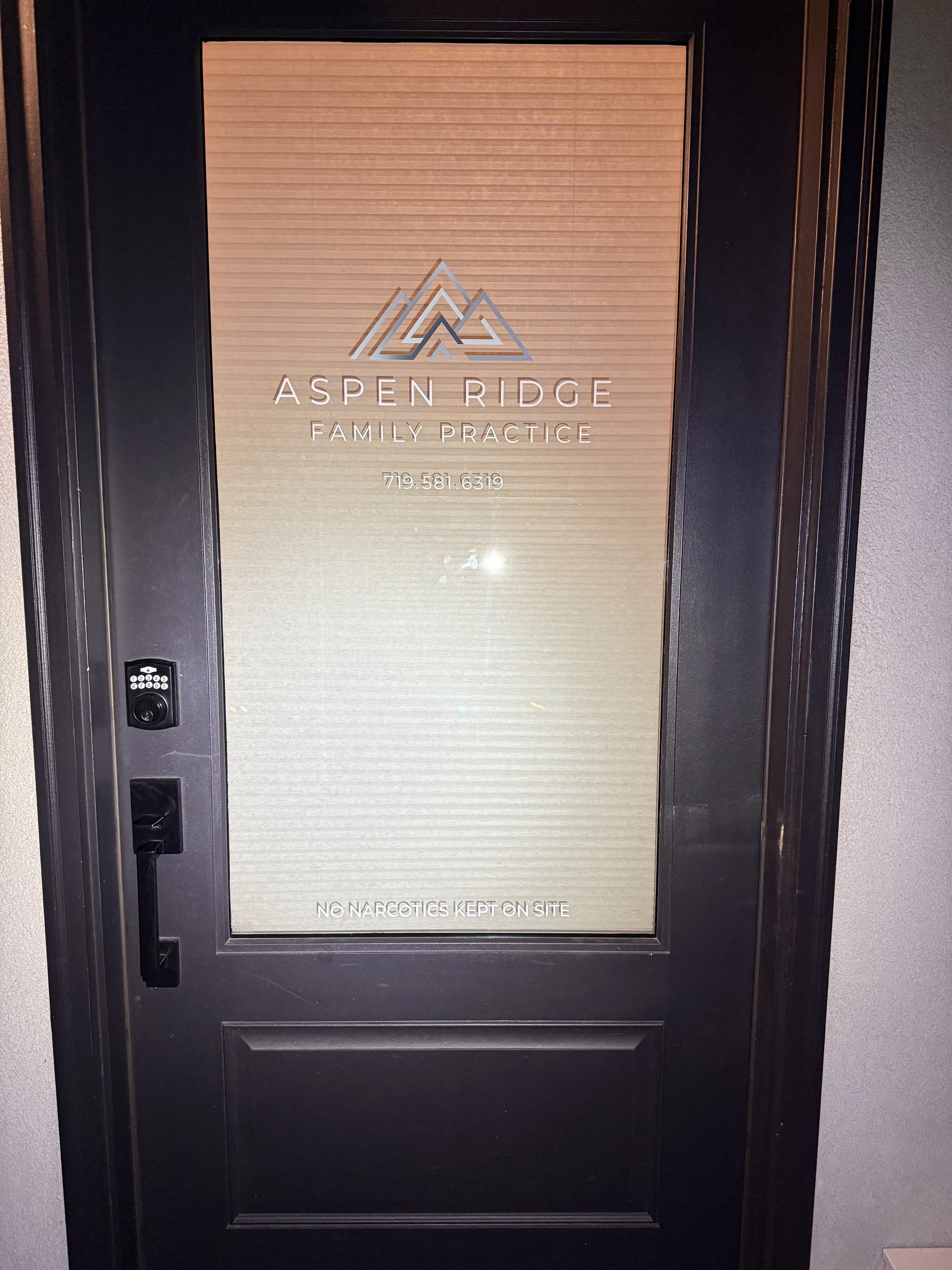 Glass door with Aspen Ridge Family Practice logo and phone number, also states 'No Narcotics Kept on Site'.
