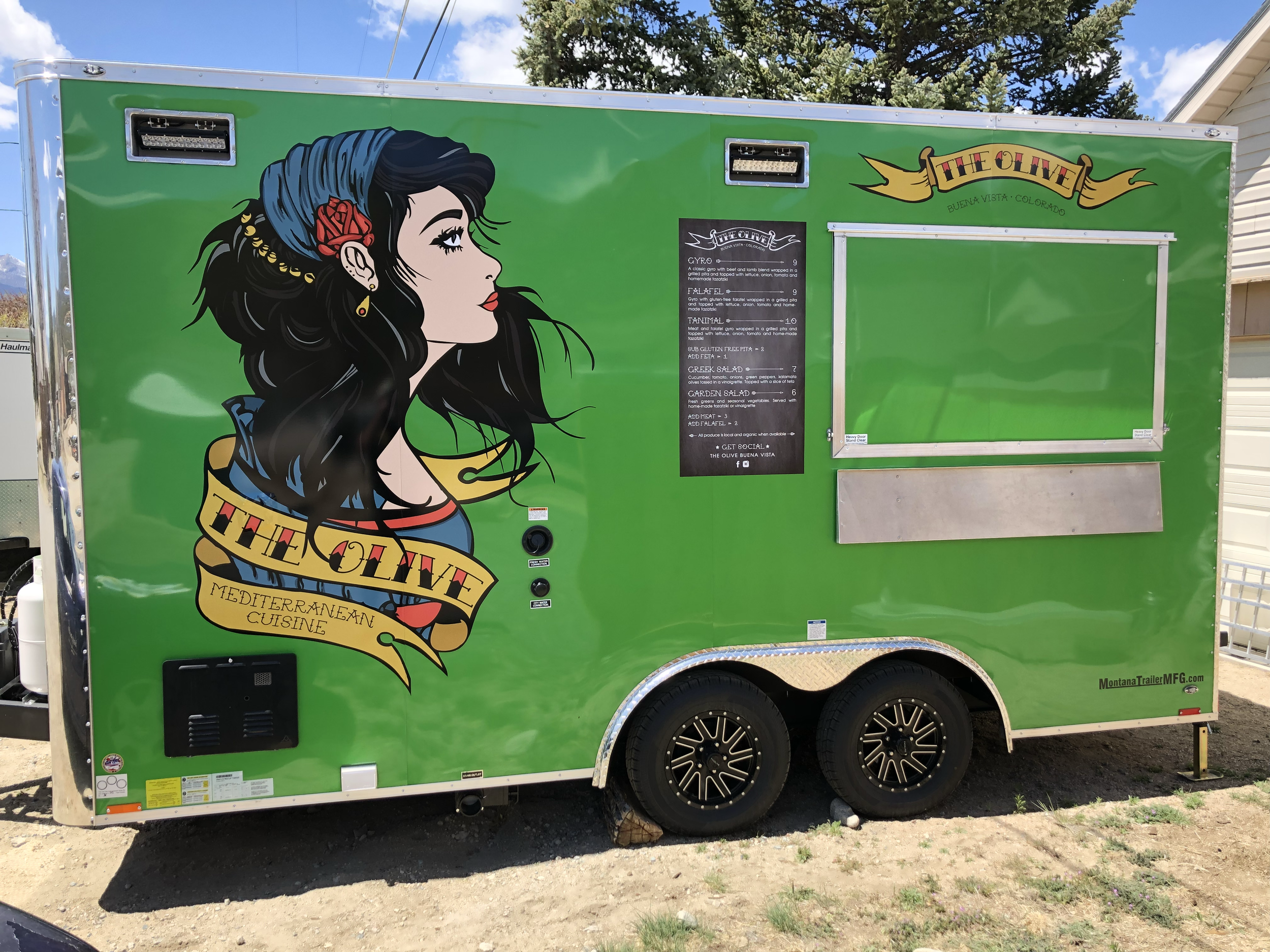 Green food truck with a colorful illustration of a woman with dark hair, a blue headscarf, and a red flower. The truck advertises Mediterranean cuisine from The Olive in Boulder, Colorado.