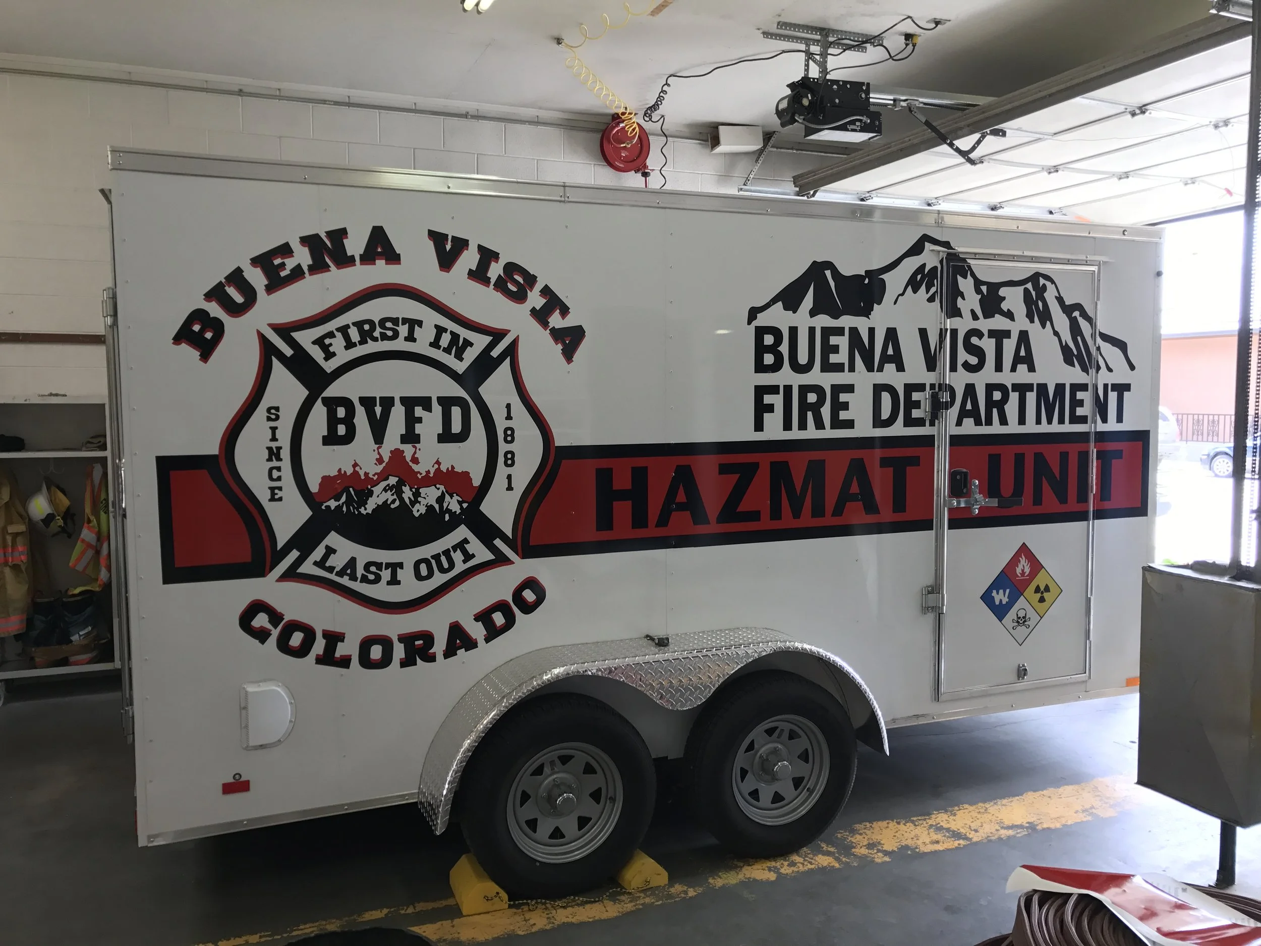 Mobile unit for the Buena Vista Fire Department Hazardous Materials Team, parked inside a fire station, marked with the department's logo, mountain graphic, and hazardous materials symbols.