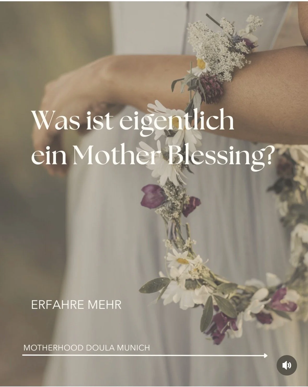 Close-up of a woman holding a floral crown made of white and purple flowers with the German text, 'Was ist eigentlich ein Mother Blessing?' which translates to 'What is actually a Mother Blessing?' There is additional text at the bottom: 'ERFAHRE MEHR' (Learn More) and 'MOTHERHOOD DOULA MUNICH'.