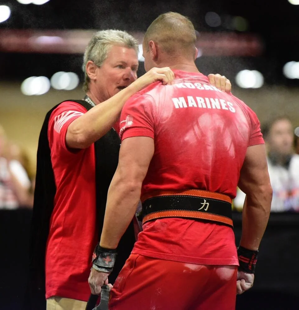 Coach LJ working with an athlete at a powerlifting competition.