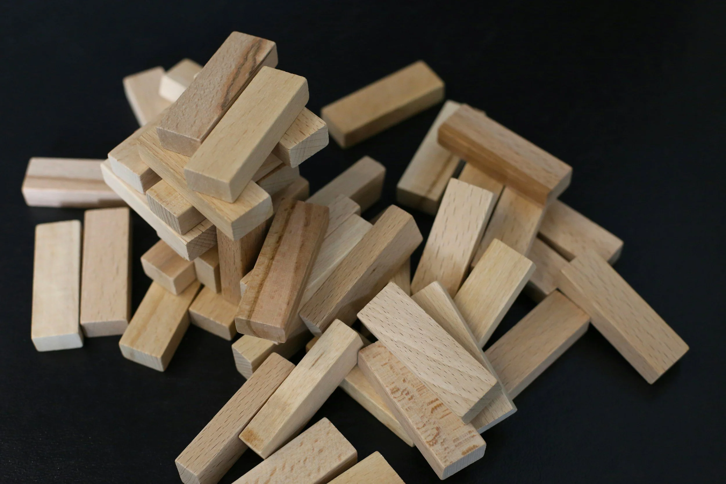 A pile of wooden rectangular blocks scattered on a black surface.