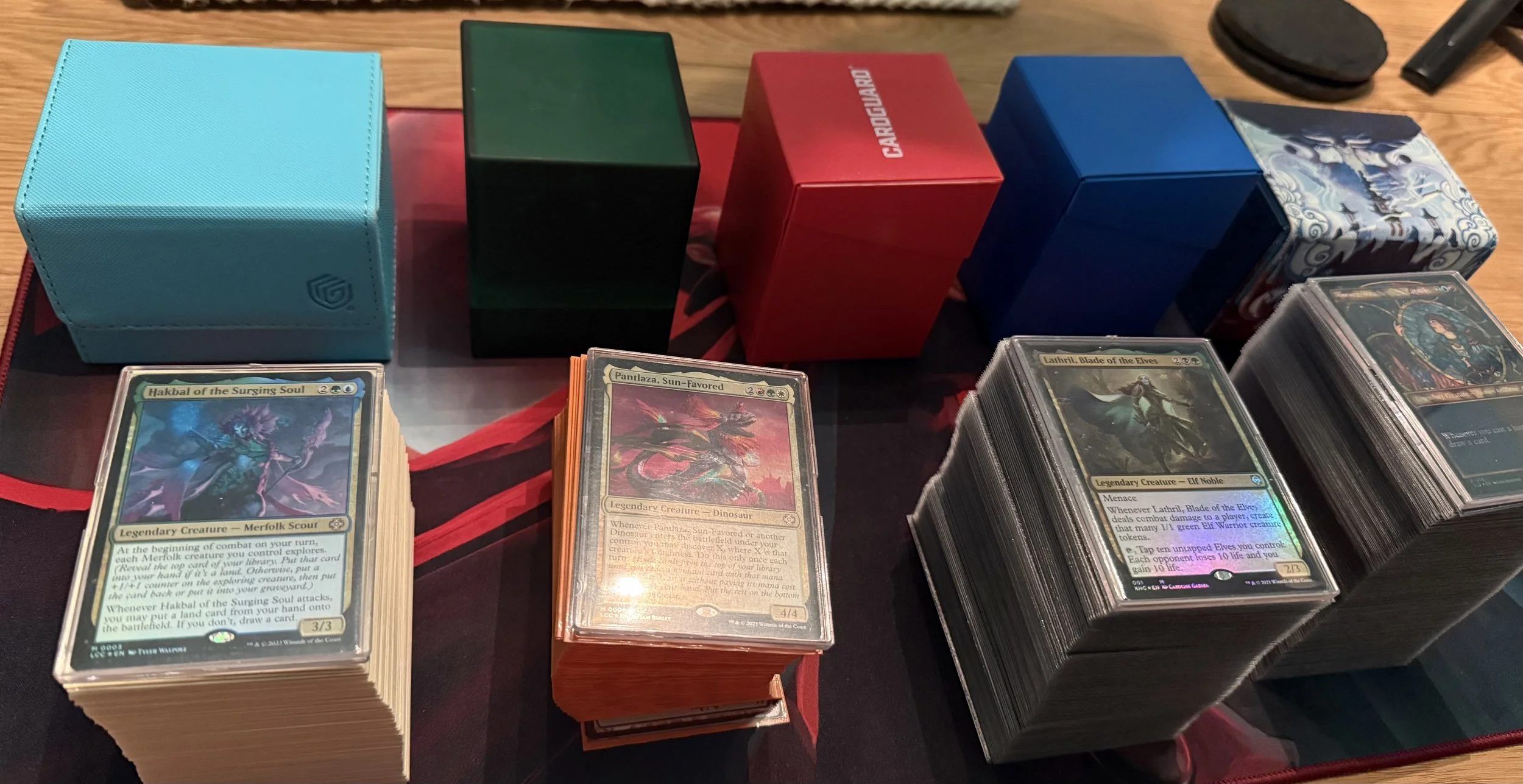 Stacks of trading cards in stacks on a table, with colorful boxes in the background.