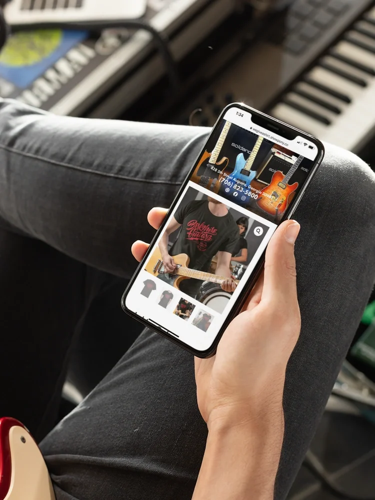 mockup-of-a-man-watching-his-iphone-xs-max-while-playing-guitar-25753.webp