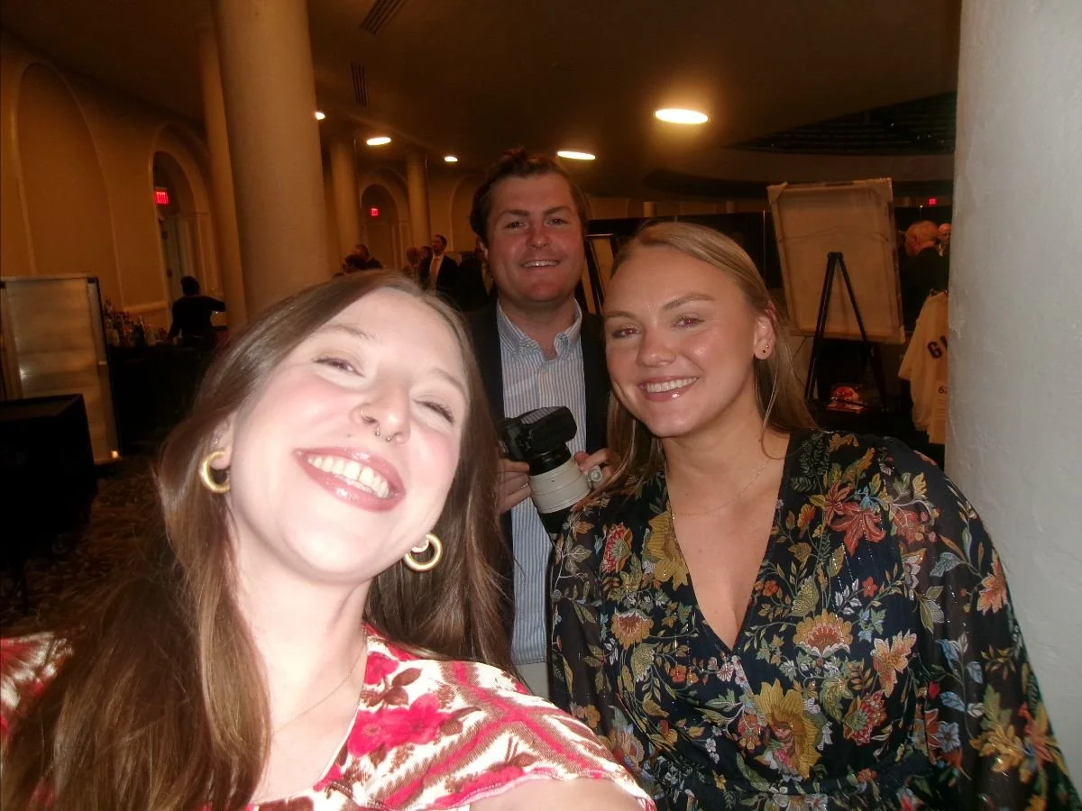 Three people--two women and a man--smile into the camera while taking a selfie.