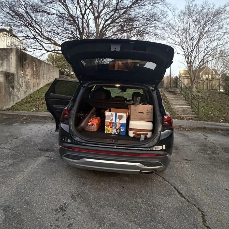 The open trunk of an SUV with luggage and snacks packed inside.